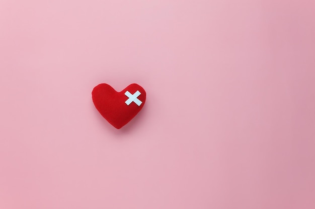 En forme de cœur avec un bandage sur un fond rose