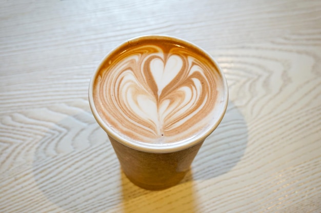 Forme de coeur de café chaud dans une tasse de papier brun