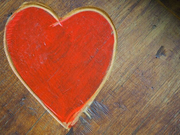 La forme d'un coeur découpé avec un couteau sur une surface en bois peinte dans un symbole rouge lumineux de l'amour