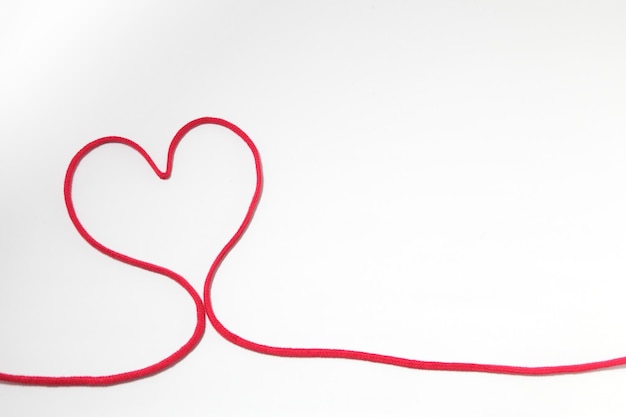 En forme de cœur avec un fil rouge sur fond blanc