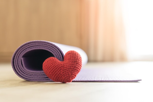 Forme de coeur de fil rouge et tapis de yoga au sol de la maison