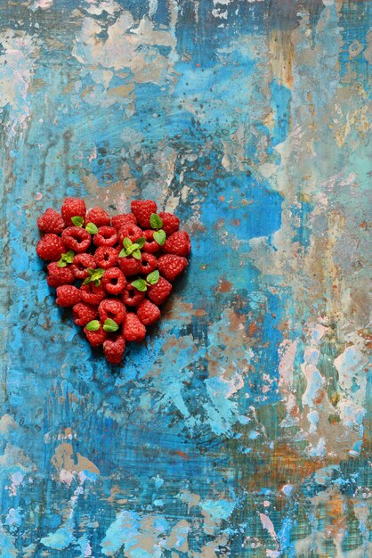 En forme de coeur de framboises premium sur fond bleu. Gros plan, vue de dessus, produit haute résolution. Concept romantique. Symbole de la Saint-Valentin