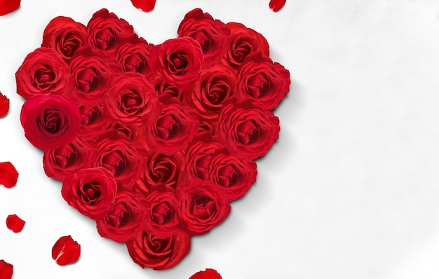 La forme de coeur de roses rouges et de pétales de rose sur le sol