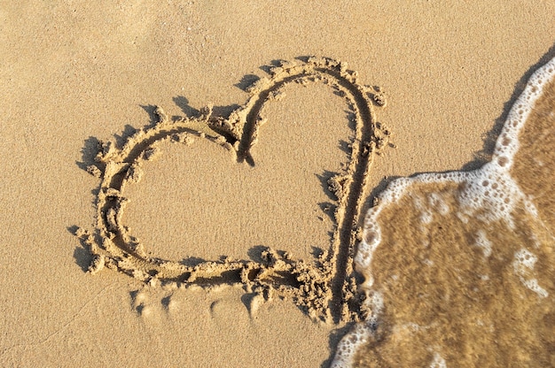 Forme de coeur sur le sable à la plage de la mer