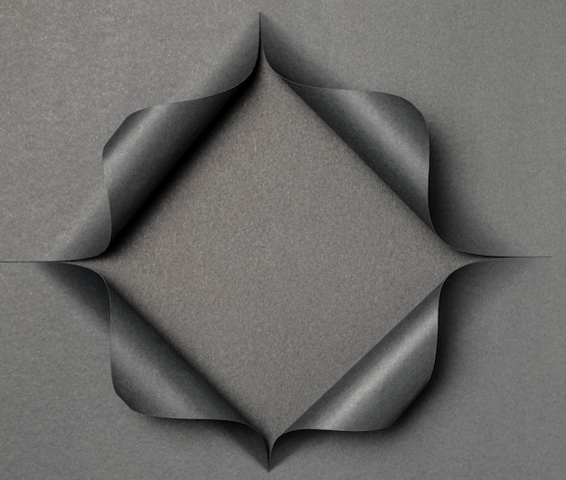 Forme grise abstraite sur papier noir déchiré