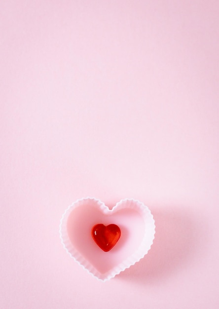 Une forme de muffin avec un coeur rouge sur fond rose