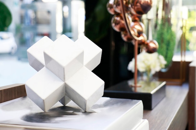 Une forme polygonale en céramique blanche posée sur le livre dans le salon pour la décoration