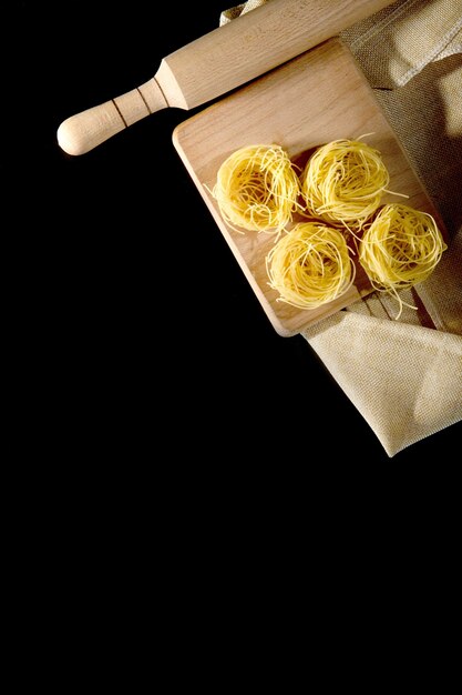 Forme de tagliatelles roulées de pâtes italiennes sur fond de pierre noire. Photo de haute qualité.