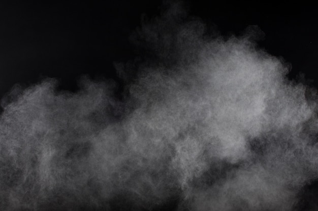 Photo formes bizarres de nuage d'explosion de poudre blanche sur fond noir. éclaboussures de particules de poussière blanche.