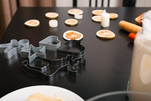 Des formes métalliques pour couper les biscuits en pain d'épice sont préparées sur une table noire.