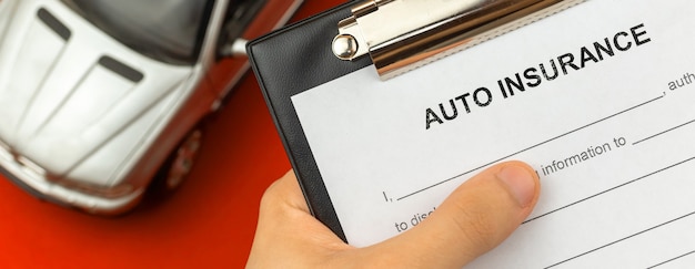 Photo formulaire d'assurance automobile en main. bureau avec jouet de voiture sur fond. photo de bannière