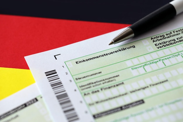 Formulaire de déclaration de déclaration de revenus annuel allemand avec un stylo sur le drapeau de près Le concept de déclaration fiscale en Allemagne