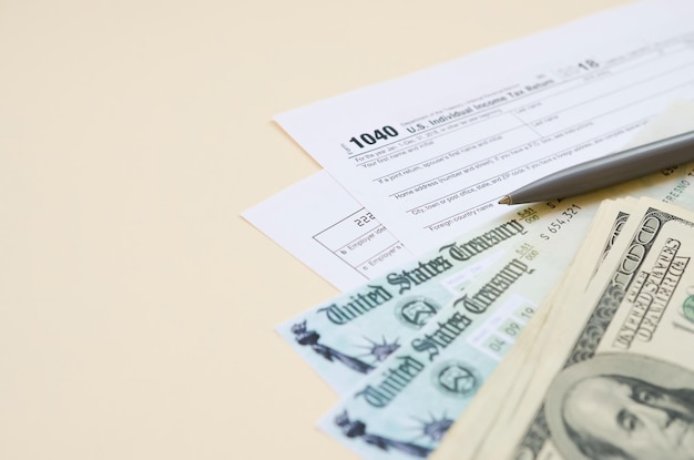 formulaire de déclaration d'impôt sur le revenu individuel avec chèque de remboursement et billets de cent dollars sur fond beige