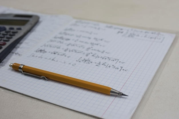 Formules mathématiques dans un cahier, un crayon et une calculatrice