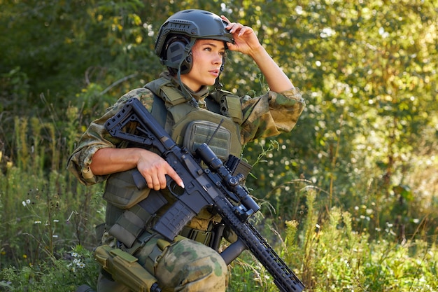 Forte brave femme soldat de l'armée avec fusil mitrailleuse debout dans la forêt