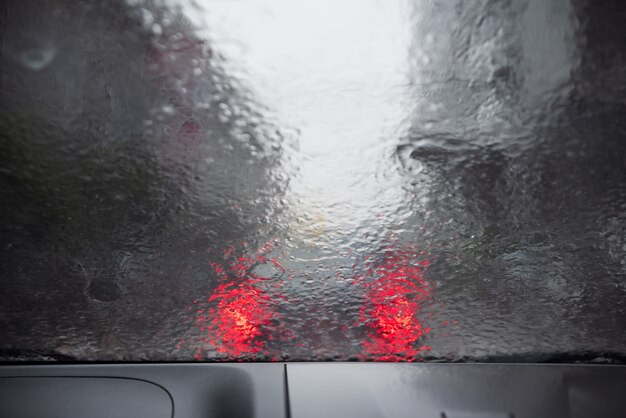 Forte pluie. Goutte de pluie sur la voiture de la fenêtre. Résumé flou bokeh de la circulation et la lumière de la voiture.