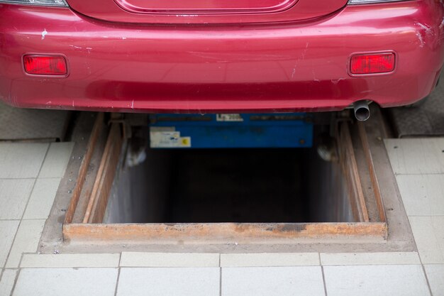 Fosse d'inspection dans le garage et voiture rouge