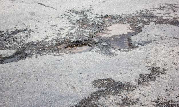 Fosse profonde sur la route Asphalte endommagé Flaques d'eau dans les nids-de-poule sur la route Autoroute endommagée Fosse dans l'asphalte Route détruite Surface de la route détruite