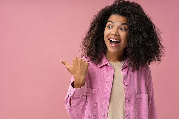 Fou de joie afro-américain pointant le doigt sur l'espace de copie isolé sur fond rose