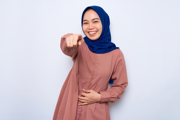 Fou de joie jeune femme musulmane asiatique en chemise rose pointant du doigt la caméra isolée sur fond blanc Les gens concept de style de vie religieux