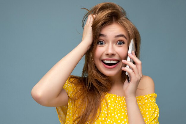 fou surpris surpris jeune femme portant des vêtements élégants décontractés debout isolé sur fond avec copie espace tenant et à l'aide de téléphone mobile en regardant la caméra.