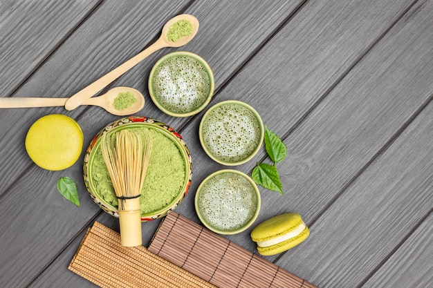 Fouet en bambou dans un bol avec de la poudre de matcha Gâteaux de macaroni au thé vert matcha et cuillères en bois sur la table
