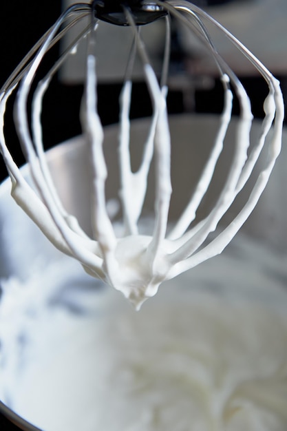Fouet en métal du mélangeur avec les restes de la cuisson de la crème fouettée
