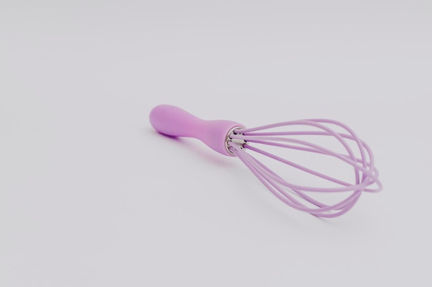 Fouet violet pour la cuisine sur fond blanc