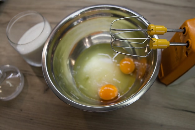 Fouets de batteur électrique devant le sucre et les œufs dans un bol