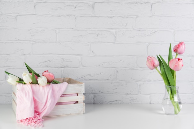 Foulard rose à l'intérieur du vase en bois et foulard en bois sur le bureau contre le mur de briques blanches