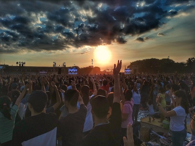 Une foule au concert de musique contre le ciel au coucher du soleil