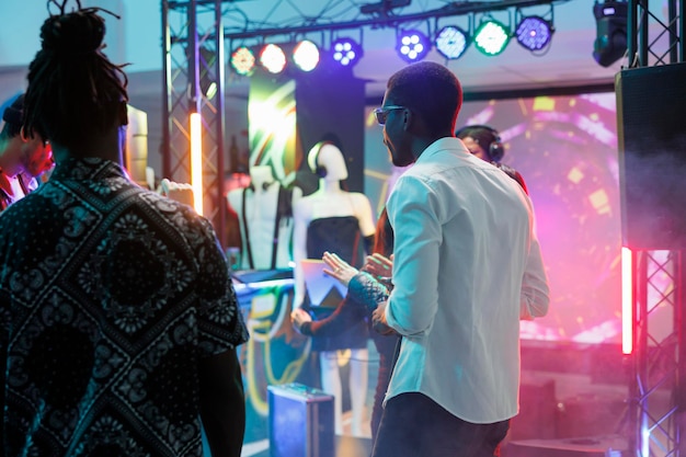 Photo la foule fait la fête sur la piste de danse et profite de la vie nocturne dans un club sombre avec des projecteurs. des gens divers dansent et s'amusent en faisant de la boîte de nuit et en fréquentant une dicothèque dans un club de nuit