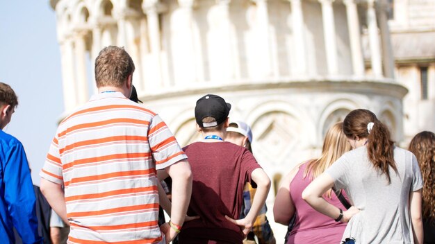 Une foule de gens reste sous la tour penchée de Pise