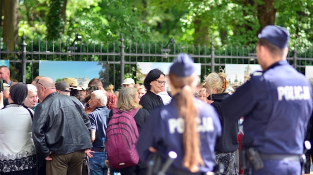 une foule de gens se tiennent devant une clôture avec la photo d'une personne portant une chemise sur laquelle est écrit « x ».