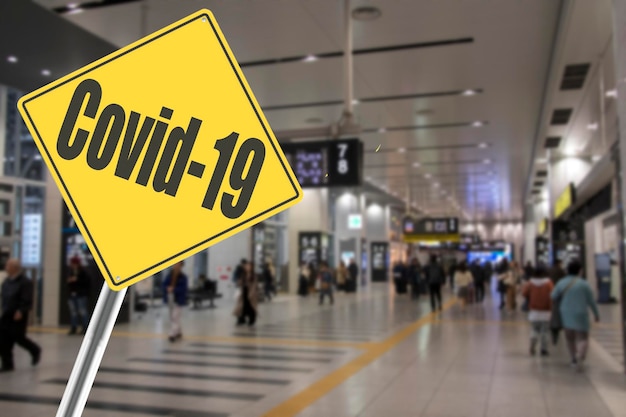 Foule de personnes à l'aéroport avec Covid19 Sign