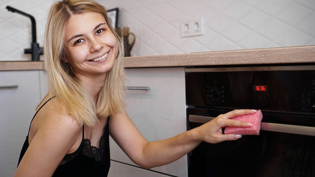 Four de nettoyage de jeune femme heureuse dans la cuisine.