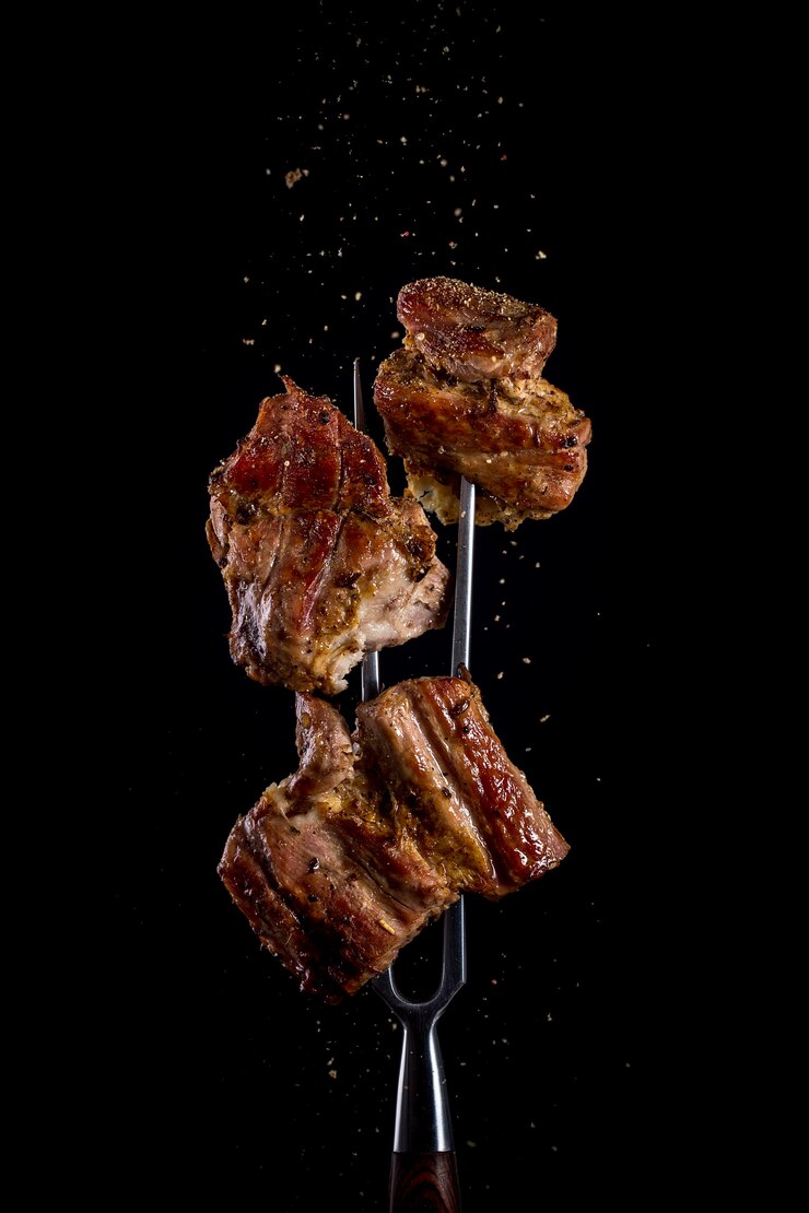 Fourche avec des morceaux de viande délicieuse grillée sur noir