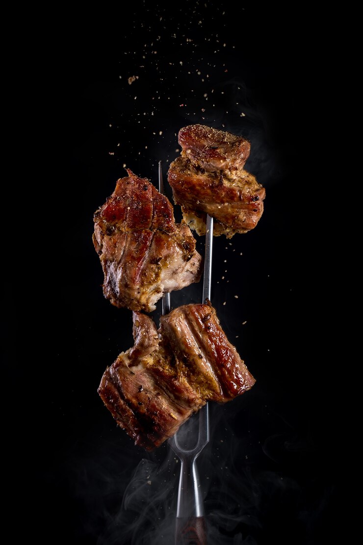 Fourche avec des morceaux de viande délicieuse grillée sur noir