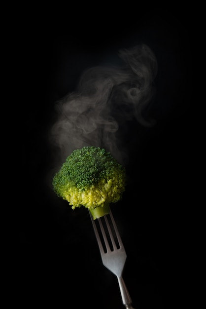 Fourchette avec brocoli bouilli et vapeur sur fond noir, copie de l'espace