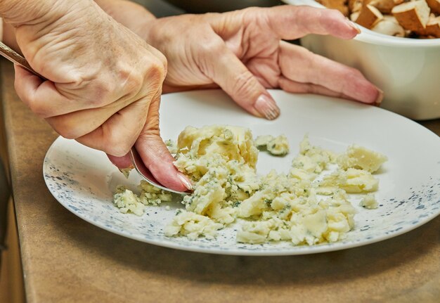 A la fourchette, le chef pétrit la purée de pommes de terre dans l'assiette.