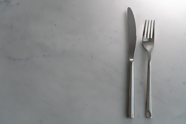 Fourchette et couteau sur fond de texture de marbre blanc. Concept pour la vaisselle et la table à manger