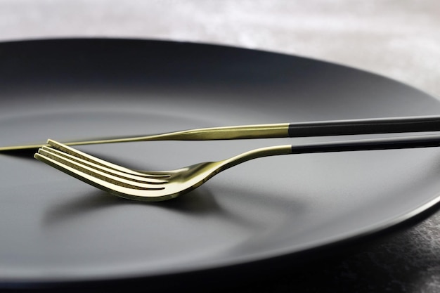 Fourchette et couteau en or fantaisie sur plaque noire.