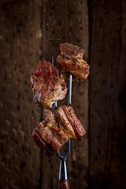 Fourchette à découper avec des morceaux de steak sur fond rustique