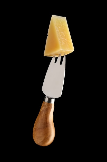 Fourchette à fromage avec un morceau de parmesan dessus isolé sur fond noir