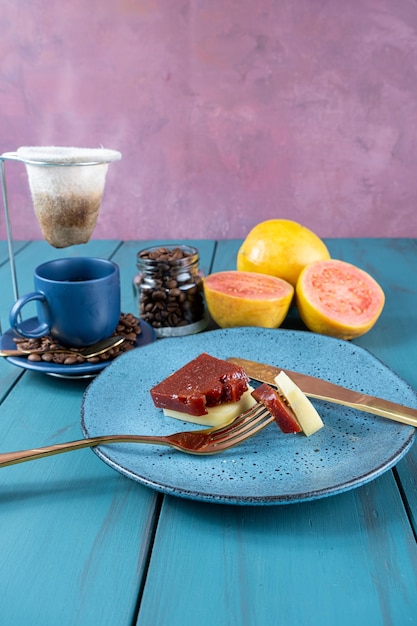 Fourchette avec des morceaux de goyave sucrée avec du fromage reposant sur une assiette à côté des haricots et une tasse de café