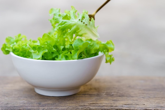 Photo une fourchette qui ramasse la salade d'un bol blanc sur un fond en bois concept d'aliments sains