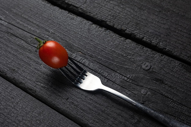 Une fourchette avec une tomate dessus sur un tableau noir