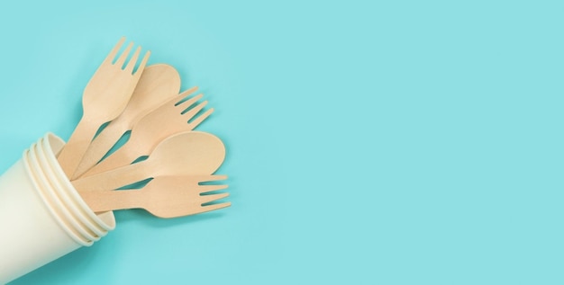 Fourchettes et cuillères jetables en bois dans une vue de dessus de gobelet en papier Mise à plat Le concept de plats écologiques