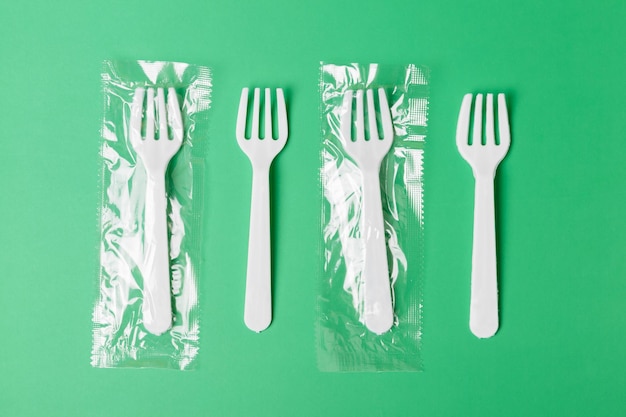 Fourchettes en plastique blanc sur fond vert Le problème mondial de la pollution de l'environnement minimalisme à plat