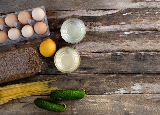 Fournitures alimentaires L'achat de nourriture sur un fond en bois Oeufs en conserve de légumes pâtes alimentaires sur un fond en bois